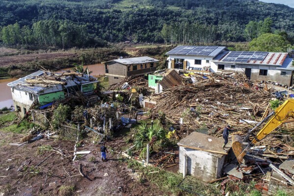 Residents walks amid destroyed houses after floods caused by a deadly cyclone in Mucum, Rio Grande do Sul state, Brazil, Wednesday, Sept. 6, 2023. An extratropical cyclone in southern Brazil caused floods in several cities. (AP Photo/Wesley Santos)