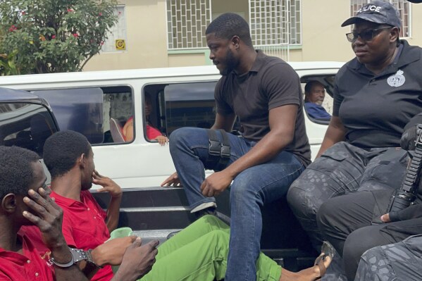 Police transport escaped prisoners Atiba Stanislaus, far left, and Trevon Robertson who are handcuffed together in Kingstown, St. Vincent and the Grenadines, Monday, March 4, 2024. The men had escaped from a police holding cell in Grenada on Feb. 18 and are suspected of hijacking a catamaran while Ralph Hendry and Kathy Brandel, who disappeared, were aboard. (AP Photo/Kenton Chance)