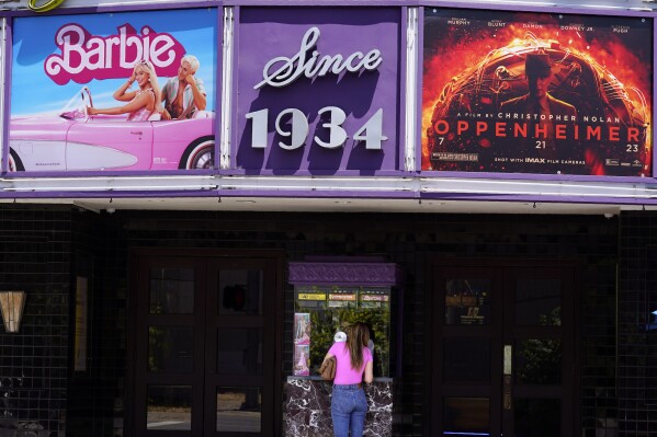 A patron buys a movie ticket underneath a marquee featuring the films "Barbie" and "Oppenheimer" at the Los Feliz Theatre, Friday, July 28, 2023, in Los Angeles. (AP Photo/Chris Pizzello)