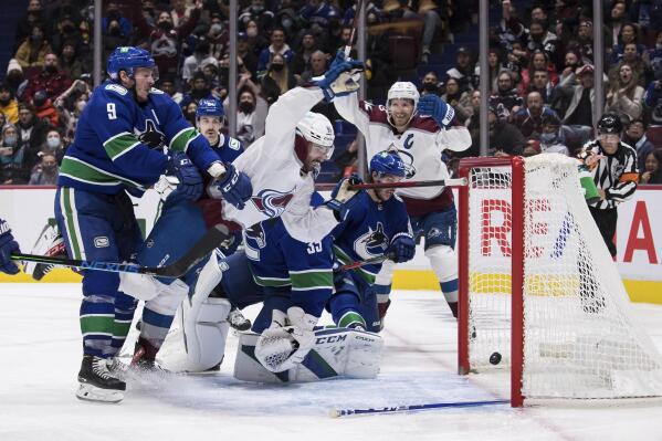 Colorado Avalanche's Nazem Kadri (91) scores against Vancouver Canucks goalie Thatcher Demko (35) and is checked into the net by J.T. Miller (9) during the third period of an NHL hockey game Wednesday, Nov. 17, 2021, in Vancouver, British Columbia. (Darryl Dyck/The Canadian Press via AP