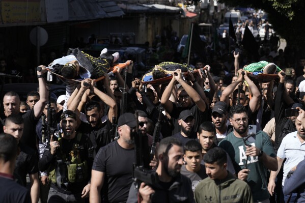 Palestinians carry bodies of militants killed in an Israeli airstrike on the refugee camp in Jenin, West Bank, during their funeral Wednesday, Oct. 25, 2023. (AP Photo/Majdi Mohammed)
