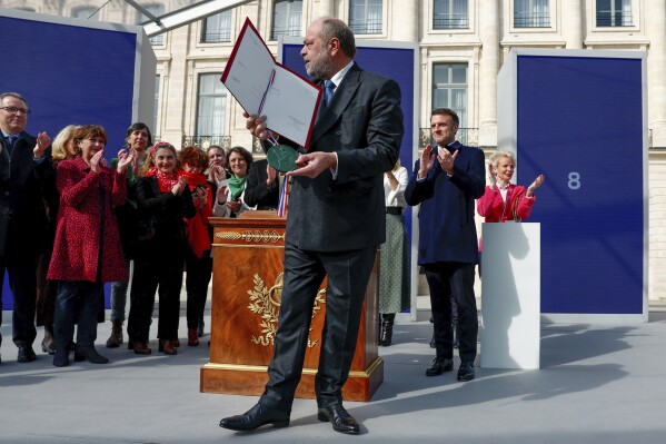 Justice Minister Eric Dupond-Moretti and French President Emmanuel Macron, background right, attendattend a ceremony to seal the right to abortion in the French constitution, on International Women's Day, at the Place Vendome, in Paris, France March 8, 2024. France inscribed the guaranteed right to abortion in its constitution Friday, a powerful message of support for women's right on International Women's Day. (Gonzalo Fuentes/Pool Photo via AP)