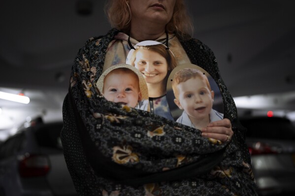 A woman holds a mask depicting the faces of Shiri Bibas and her sons Kfir and Ariel, Israelis who are being held hostage in the Gaza Strip by the Hamas militant group, during a protest demanding the release of the hostages from Hamas captivity, in Tel Aviv, Israel, Wednesday, Feb. 21, 2024. Relatives of hostages still being held by Hamas and other militant groups have endured a nightmare. Nearly five months into the war that began with Hamas' deadly Oct. 7 attack on Israel, the hostages relatives hold on to hope that they will be freed but are growing increasingly desperate for a resolution. (AP Photo/Oded Balilty)
