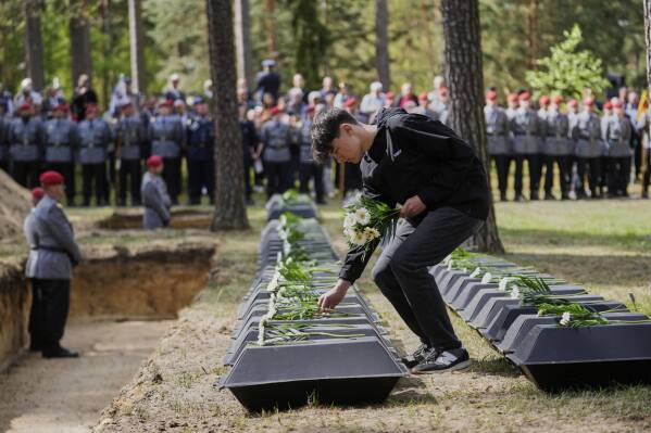 A student pays tribute to the the remains of fallen German soldiers of WWII during a funeral service at a memorial site for fallen soldiers in Halbe, Germany, Wednesday, April 30, 2025. (AP Photo/Ebrahim Noroozi)