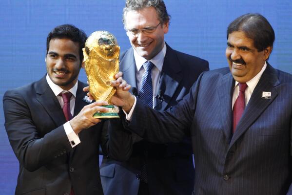 FILE - Mohamed bin Hamad Al-Thani, left, Chairman of the 2022 bid committee, and Sheikh Hamad bin Khalifa Al-Thani, Emir of Qatar, hold the World Cup trophy in front of FIFA Secretary General Jerome Valcke after the announcement that Qatar will host the 2022 soccer World Cup, on Dec. 2, 2010, in Zurich, Switzerland. Qatar has for years employed a former CIA officer to help spy on soccer officials as part of an aggressive effort to win and hold on to the 2022 World Cup tournament, an investigation by The Associated Press has found. (AP Photo/Anja Niedringhaus, File)