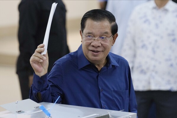 FILE- Cambodian Prime Minister Hun Sen of the Cambodian People's Party (CPP) raises a ballot before voting at a polling station at Takhmua in Kandal province, southeast Phnom Penh, Cambodia, on July 23, 2023. Longtime Cambodian leader Hun Sen says he will step down in three weeks as prime minister and hand the position to his oldest son. (AP Photo/Heng Sinith, File)