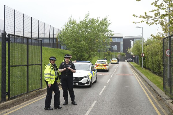 Police stand outside the Birley Academy in Sheffield, northern England, on Wednesday, May 1, 2024. A 17-year-old boy was arrested on suspicion of attempted murder after three people were assaulted with a sharp object at a secondary school in northern England, South Yorkshire Police said Wednesday. Two adults suffered minor injuries and an injured child was being examined, police said. (Dominic Lipinski/PA via AP)