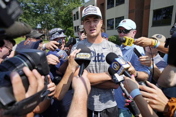 Pittsburgh Steelers quarterback Kenny Pickett, center, is surrounded by media after arriving for the NFL football team's training camp in Latrobe, Pa., Wednesday, July 26, 2023. (AP Photo/Gene J. Puskar)