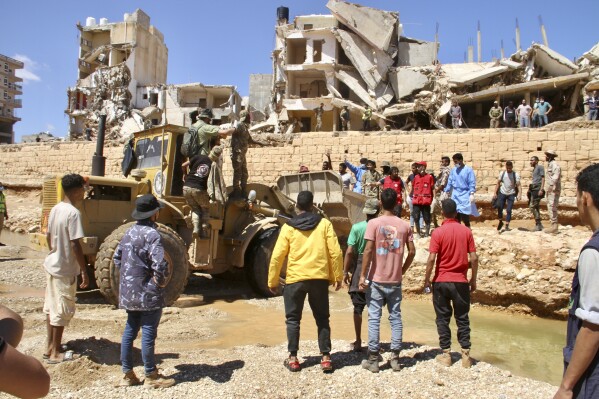 People look for survivors in Derna, Libya, Wednesday, Sept.13, 2023. Search teams are combing streets, wrecked buildings, and even the sea to look for bodies in Derna, where the collapse of two dams unleashed a massive flash flood that killed thousands of people. (AP Photo/Yousef Murad)