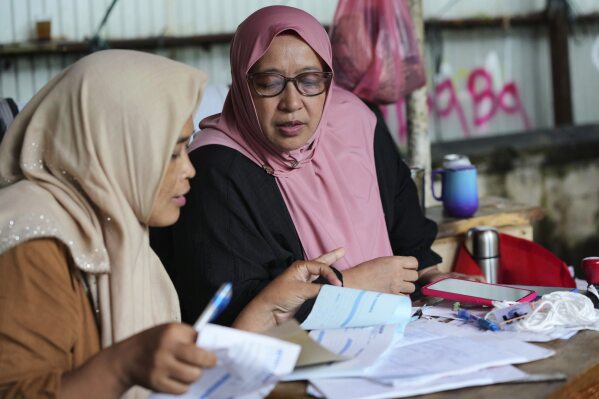 Nina Herlina reviews her trading record ahead of of the Eid al-Adha festival, at her livestock stall in Jakarta, Indonesia, Wednesday, June 4, 2025.(AP Photo/Achmad Ibrahim)