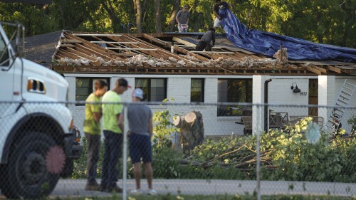 Des travailleurs peinent à mettre une bâche sur un toit endommagé après qu'une tornade s'est abattue dans plusieurs zones de Greenwood, Ind., dimanche après-midi, 25 juin 2023. (Jenna Watson/The Indianapolis Star via AP)