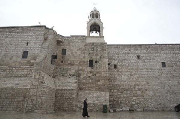 Un sacerdote passa davanti alla Chiesa della Natività, tradizionalmente ritenuta il luogo di nascita di Gesù, la vigilia di Natale, nella città di Betlemme, in Cisgiordania, domenica 24 dicembre 2023. Betlemme sta assistendo a un Natale tranquillo dopo i funzionari della Chiesa di Gesù .  La tradizionale città natale ha deciso di abbandonare i festeggiamenti a causa della guerra tra Israele e Hamas.  (AP Photo/Mahmoud Alyan)