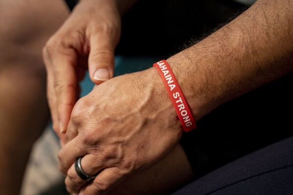 Kawehi Akiona wears a wristband with the words "Lahaina Strong" at his home, Thursday, Dec. 12, 2024, in Wailuku, Hawaii. Akiona has been wearing this wristband since the Lahaina wildfire. (AP Photo/Mengshin Lin)
