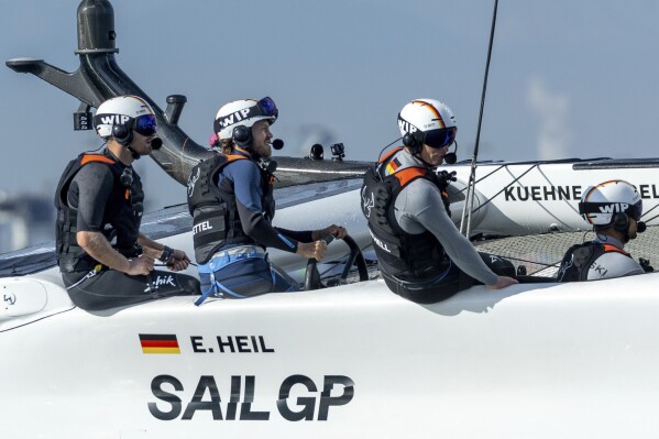 In this photo provided by SailGP, Sebastian Vettel, four-time Formula One world champion and investor of Germany SailGP Team, takes control of the wheel onboard the Germany SailGP Team F50 catamaran as he joins the Germany SailGP Team for a sixth sailor experience on Race Day 1 of the Oracle Los Angeles Sail Grand Prix at the Port of Los Angeles, Saturday, July 22, 2023. (Simon Bruty/SailGP via AP)