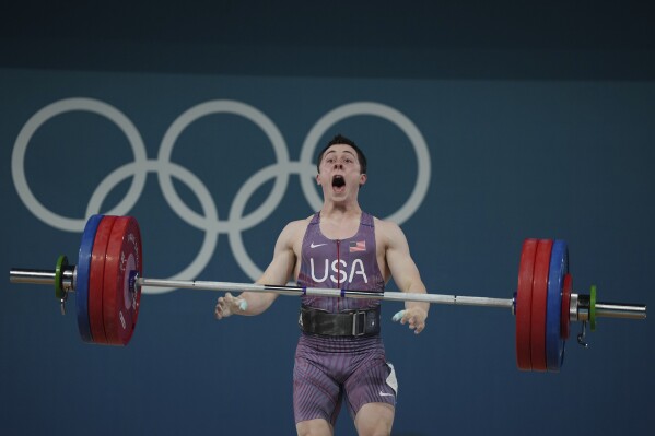 Hampton Morris of the United States reacts as he competes during the men's 61kg weightlifting event at the 2024 Summer Olympics, Wednesday, Aug. 7, 2024, in Paris, France. (AP Photo/Kin Cheung)