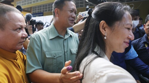 Hun Manet, center, of the Cambodian People's Party (CPP), son of Cambodia Prime Minister Hun Sen, also army chief, walks outside a polling station together with his wife, Pich Chanmony, right, before voting at a polling station in Phnom Penh, Cambodia, Sunday, July 23, 2023. Hun Sen has suggested he will hand off the premiership during the upcoming five-year term to his oldest son, Hun Manet, perhaps as early as the first month after the elections. (AP Photo/Heng Sinith)