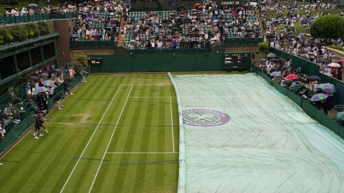 Ground staff pull over the rain cover onto Court no. 18 on day six of the Wimbledon tennis championships in London, Saturday, July 8, 2023. (AP Photo/Alberto Pezzali)