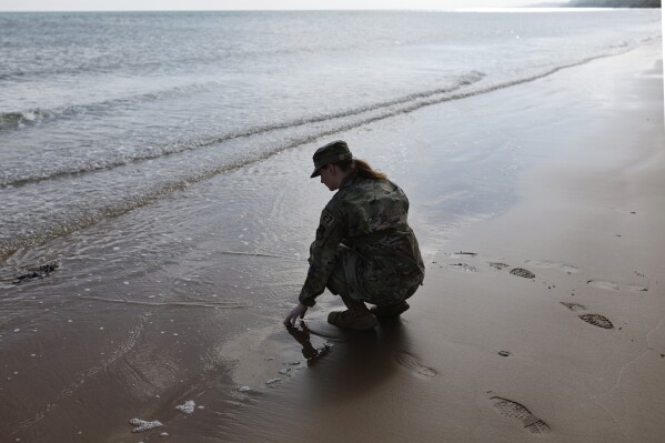 An American soldier touches the sand on Omaha Beach, Tuesday, June 4, 2024 in Normandy. World War II veterans from across the United States as well as Britain and Canada are in Normandy this week to mark 80 years since the D-Day landings that helped lead to Hitler's defeat. (AP Photo/Jeremias Gonzalez)