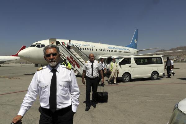 Pilots of Ariana Afghan Airlines walk on the tarmac after landing at Hamid Karzai International Airport in Kabul, Afghanistan, Sunday, Sept. 5, 2021. Some domestic flights have resumed at Kabul's airport, with the state-run Ariana Afghan Airlines operating flights to three provinces. (AP Photo/Wali Sabawoon)