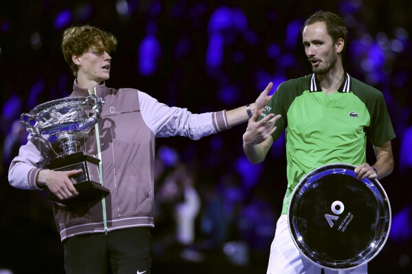 Jannik Sinner, left, of Italy gestures as he holds the Norman Brookes Challenge Cup after defeating Daniil Medvedev, right, of Russia in the men's singles final at the Australian Open tennis championships at Melbourne Park, in Melbourne, Australia, Sunday, Jan. 28, 2024. (AP Photo/Asanka Brendon Ratnayake)