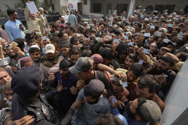 Police officers try to control immigrants, mostly Afghans, gather to verify their data at a counter of Pakistan's National Database and Registration Authority, in Karachi, Pakistan, Tuesday, Nov. 7, 2023. Pakistan government launched a crackdown on migrants living in the country illegally as a part of the new measure which mainly target all undocumented or unregistered foreigners. (AP Photo/Fareed Khan)
