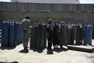 Women wait inside a factory to get their oxygen cylinders refilled from a privately owned oxygen factory, in Kabul, Afghanistan, Saturday, June 19, 2021. Health officials say Afghanistan is fast running out of oxygen as a deadly third surge of COVID worsen. (AP Photo/Rahmat Gul)