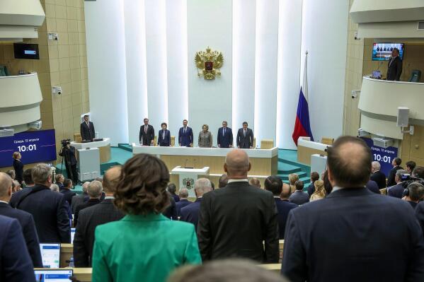 In this handout photo released by The Federal Assembly of The Russian Federation, members of the Federal Assembly of The Russian Federation listen to the national anthem as they attend a session in Moscow, Russia, Wednesday, April 12, 2023. The upper house of Russian parliament has swiftly approved a bill that would allow authorities to issue electronic summons to draftees and reservists amid the fighting in Ukraine. (The Federal Assembly of The Russian Federation via AP)