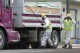 FILE - Unidentified road workers wear protective gear against possible asbestos contamination as they load material from a road resurfacing project in downtown Libby, Mont., April 28, 2011. A health clinic in the Montana town that's plagued by deadly asbestos contamination is liable for almost $6 million in penalties and damages after it submitted hundreds of false claims for government benefits. (AP Photo/Matthew Brown, File)