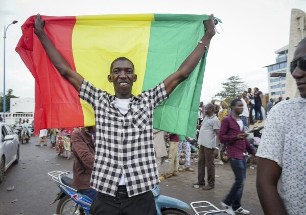 A man holds a national flag as he celebrates with others in the streets in the capital Bamako, Mali Tuesday, Aug. 18, 2020. Mutinous soldiers detained Mali's president and prime minister Tuesday after surrounding a residence and firing into the air in an apparent coup attempt after several months of demonstrations calling for President Ibrahim Boubacar Keita's ouster. (AP Photo)