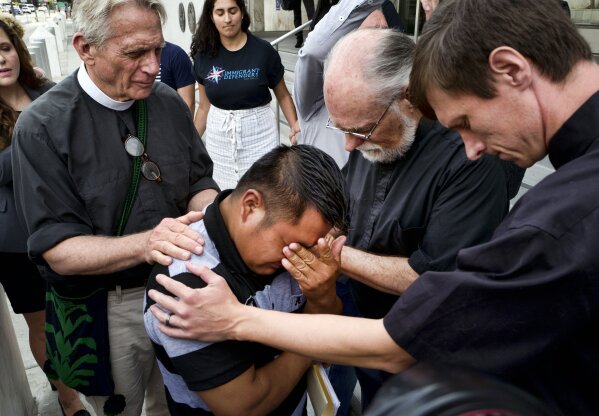 
              Hermelindo Che Coc, of Guatemala, kneels as Father Tom Carey, left, Rev. David Farley and Rev. Matthias Peterson-Brandt, right, pray over him before a required check-in with immigration enforcement authorities on Tuesday, July 10, 2018 in Los Angeles. Che Coc says his 6-year-old son feared he was dead after U.S. authorities separated the pair on the U.S.-Mexico border after they crossed into Texas in May. He says authorities told him he would be detained and his son was sent to a shelter in New York. (AP Photo/Richard Vogel)
            