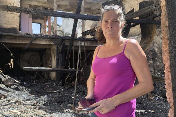 Emilie holds her burned passport in her charred home following riots in Pointe-a-Pitre, Guadeloupe island, Sunday, Nov.21, 2021. French authorities are sending police special forces to the Caribbean island of Guadeloupe, an overseas territory of France, as protests over COVID-19 restrictions erupted into rioting. In Pointe-a-Pitre, the island's largest urban area, clashes left three people injured, including a 80-year-old woman who was hit by a bullet while on her balcony. A firefighter and a police officer were also injured and several shops were looted there and in other towns. (AP Photo/Elodie Soupama)