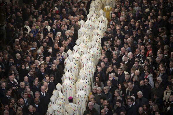 Guest watch clergy members leaving the inaugural mass at Notre Dame Cathedral, hosting its first Mass since the catastrophic fire of 2019,, Sunday, Dec. 8, 2024 in Paris. (AP Photo/Alessandra Tarantino, Pool)