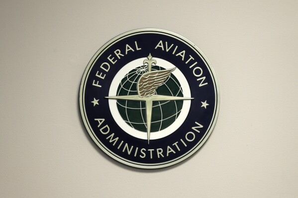 FILE - A Federal Aviation Administration sign hangs in the tower at John F. Kennedy International Airport in New York, March 16, 2017. Federal officials are investigating an incident Friday, Aug. 11, 2023, in which a private plane was told to abort its landing to avoid hitting a Southwest Airlines jet that was using the same runway to take off in the latest in a series of recent close calls between planes. (AP Photo/Seth Wenig, File)