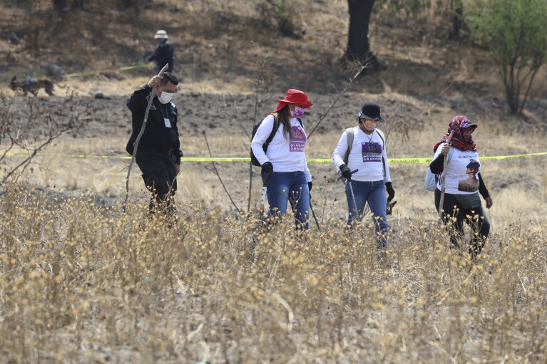 2024 年 5 月 1 日星期三，一名警察陪同携带挖掘工具的妇女在墨西哥城郊区特拉瓦克发现了一个秘密火葬场。右三是杰奎琳·帕尔梅罗斯，她正在寻找她的女儿。自 2020 年以来一直失踪。在墨西哥城，右数第二个 她是玛丽亚·德·耶稣·索里亚 (Maria de Jesus Soria)，她的女儿于 2016 年在韦拉克鲁斯失踪，她的遗体于 2022 年归还给她。（美联社照片/Ginnette Riquelme）