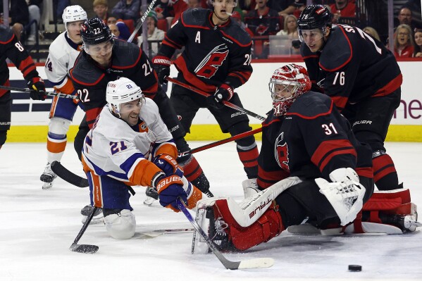 New York Islanders' Kyle Palmieri (21) stretches to shoot the puck wide of Carolina Hurricanes goaltender Frederik Andersen (31) with Hurricanes' Brett Pesce (22) and Brady Skjei (76) nearby during the third period in Game 1 of an NHL hockey Stanley Cup first-round playoff series in Raleigh, N.C., Saturday, April 20, 2024. (AP Photo/Karl B DeBlaker)