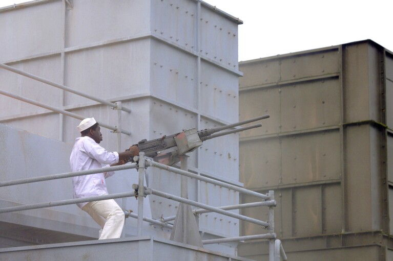 This image released by National Geographic shows Abdul Sulaiman, portraying mess attendant Doris Miller, useing an anti-aircraft gun on the USS West Virginia in a WW2 historic reenactment scene for the series "Erased: WW2's Heroes of Color." (National Geographic via AP)