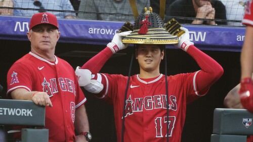 Los Angeles Angels starting pitcher Shohei Ohtani, right, holds the home run hat as manager Phil Nevin stands next to him, after Mike Trout hit a solo home run off Colorado Rockies starting pitcher Kyle Freeland during the fifth inning of a baseball game Friday, June 23, 2023, in Denver. (AP Photo/David Zalubowski)