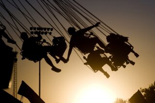 FILE - In this July 23, 2009 file photo, children are silhouetted by the setting sun as they ride a swing ride during the Canyon County Fair in Caldwell, Idaho. New results published Monday, Dec. 9, 2019, in JAMA Pediatrics from the largest long-term study of brain development and children’s health raise provocative questions about obesity and brain function. (Greg Kreller/The Idaho Press-Tribune via AP, File)
