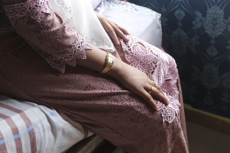 Rohingya child bride, B, age 14, sits on a bed in an apartment in Kuala Lumpur, Malaysia, on Oct. 4, 2023. B came to Malaysia in 2023 to marry an older man. Her husband wants her to get pregnant, but she says she doesn't feel ready. "I still feel like a girl." (AP Photo/Victoria Milko)