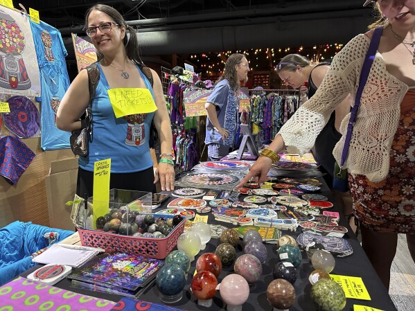This photo shows Kim Mancini of Reading, Pa. selling Phish inspired posters and stickers during PhanArt on Saturday, April 20, 2024, at the Brooklyn Bowl in Las Vegas. (AP Photo/Josh Cornfield)