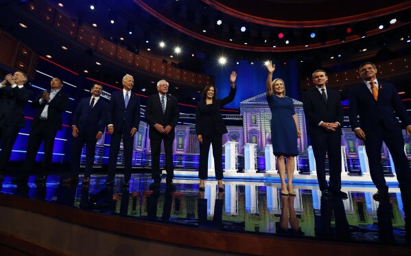 CORRECTS SPELLING OF GILLIBRAND'S FIRST NAME TO KIRSTEN, INSTEAD OF KRISTEN; CORRECTS BENNET'S TITLE TO SEN., INSTEAD OF FORMER SEN.Democratic presidential candidates from left, former Colorado Gov. John Hickenlooper, entrepreneur Andrew Yang, South Bend Mayor Pete Buttigieg, former Vice-President Joe Biden, Sen. Bernie Sanders, I-Vt., Sen. Kamala Harris, D-Calif., Sen. Kirsten Gillibrand, D-N.Y., Colorado Sen. Michael Bennet and Rep. Eric Swalwell, D-Calif., wave as they enter the stage for the second night of the Democratic primary debate hosted by NBC News at the Adrienne Arsht Center for the Performing Arts, Thursday, June 27, 2019, in Miami. (AP Photo/Brynn Anderson)