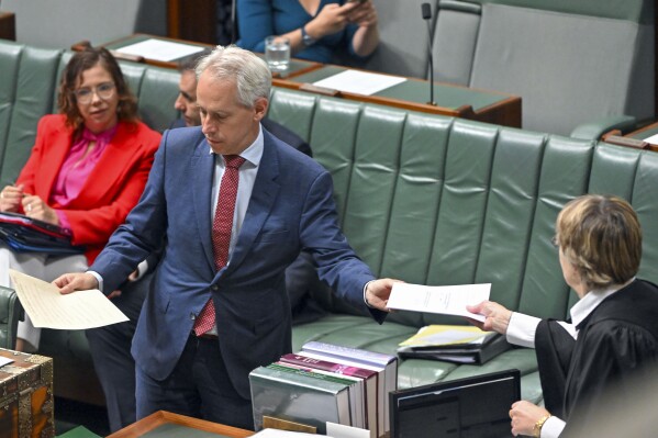 Australian Minister for Immigration Andrew Giles presents the emergency Migration Amendment Bill in the House of Representatives at Parliament House in Canberra, Australia, Thursday, Nov. 16, 2023. High-risk migrants will face up to five years in prison for breaching their visa conditions under emergency laws that have been introduced to Parliament in response to a landmark High Court ruling that they can't be held in detention indefinitely. (Mick Tsikas/AAP Image via AP)