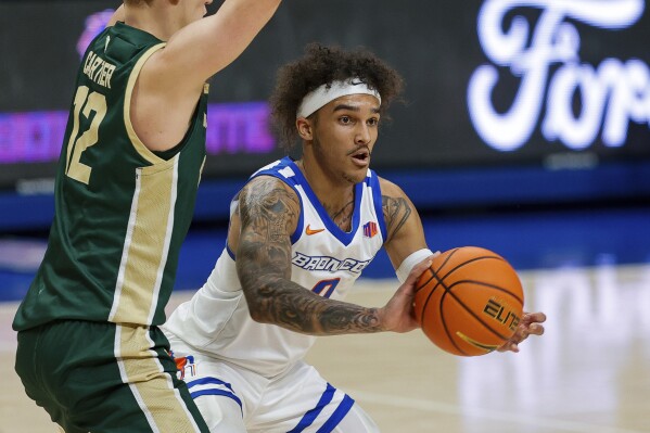 Boise State guard Roddie Anderson III (0) passes the ball away from Colorado State forward Patrick Cartier (12) during the first half of an NCAA college basketball game Tuesday, Jan. 9, 2024, in Boise, Idaho. (AP Photo/Steve Conner)