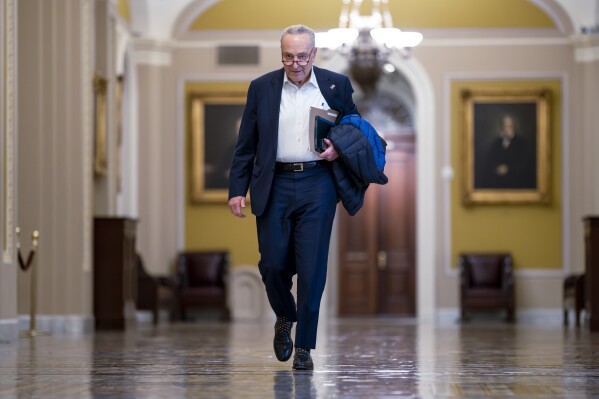 Senate Majority Leader Chuck Schumer, D-N.Y., arrives as the Senate prepares to take a procedural vote on an emergency spending package that would provide military aid to Ukraine and Israel, replenish U.S. weapons systems and provide food, water and other humanitarian aid to civilians in Gaza, at the Capitol in Washington, Sunday, Feb. 11, 2024. (AP Photo/J. Scott Applewhite)