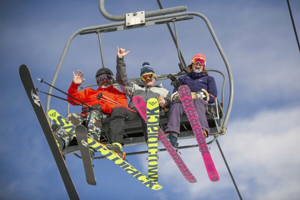 FILE - In this Nov. 23, 2018, file photo, skiers wave off of the Big Burn lift at Aspen Snowmass Mountain in Colorado. Ski resorts are grappling with how to help prevent the spread of the coronavirus while most planned to stay open as they try to salvage the final month-plus of the ski season. Some resorts are closing enclosed gondolas or aerial trams while others are encouraging skiers to ride lifts with only people they know as they adhere to social distancing guidelines. (Anna Stonehouse/The Aspen Times via AP, File)