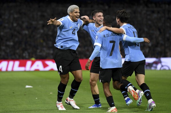 Uruguay's Ronald Araujo, left, celebrates with teammates scoring the opening goal against Argentina with teammates during a qualifying soccer match for the FIFA World Cup 2026 at La Bombonera stadium in Buenos Aires, Argentina, Thursday, Nov. 16, 2023. (AP Photo/Gustavo Garello)