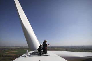 Technicians kneel on a wind turbine of a wind turbine at the Heinsberg-Straeten wind farm in Heinsberg, Germany, Tuesday, March 22, 2022. (Oliver Berg/dpa via AP)