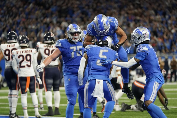 Detroit Lions wide receiver Amon-Ra St. Brown (14) jumps on running back David Montgomery (5) after Montgomery's 1-yard rushing touchdown during the second half of an NFL football game against the Chicago Bears, Sunday, Nov. 19, 2023, in Detroit. (AP Photo/Paul Sancya)