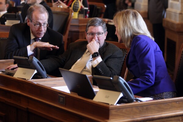 Kansas state Reps. Mark Schreiber, left, R-Emporia; Carl Maughan, center, R-Colwich, and Susan Humphries, right, R-Wichita, confer during a House vote on overriding Democratic Gov. Laura Kelly's veto of a GOP tax plan, Tuesday, Feb. 20, 2024, at the Statehouse in Topeka, Kan. Schreiber was among five House Republicans who voted against overriding Kelly's veto, helping to sustain it. (AP Photo/John Hanna)