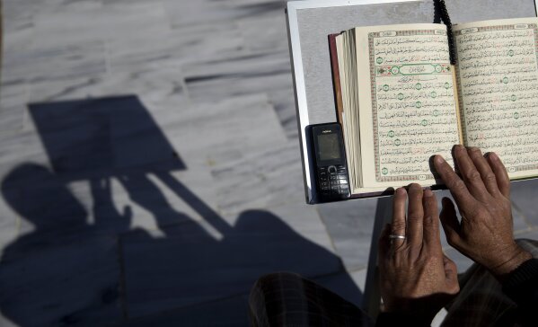 FILE - In this May 8, 2019 file photo, a Palestinian reads verses of the Quran, Islam's holy book, during the month of Ramadan at Al Emari Mosque in Gaza City. The Muslim holy month of Ramadan, with its long days of fasting and prayer meant to draw worshippers closer to God and away from worldly distractions, is being reshaped by technology. People in the Middle East are spending close to 58 million more hours on Facebook and watching more YouTube videos than at any other time of the year, making Ramadan the biggest moment of the year for advertisers. (AP Photo/Hatem Moussa, File)